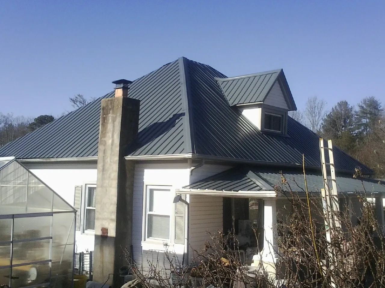 Dark blue standing seam metal roof on a white farmhouse with dormer — Slate & Tile Roof Repair by Roofing Brothers in Brock