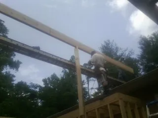 Carpenter setting a ridge beam over a new addition frame — Ice Dam Removal by Roofing Brothers in Brock