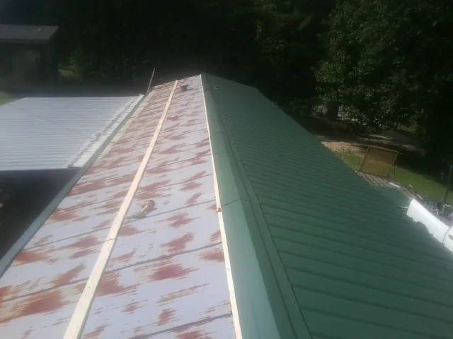Old rusted panels beside newly installed green metal roofing — Wind Damage Roof Repair by Roofing Brothers in Brock