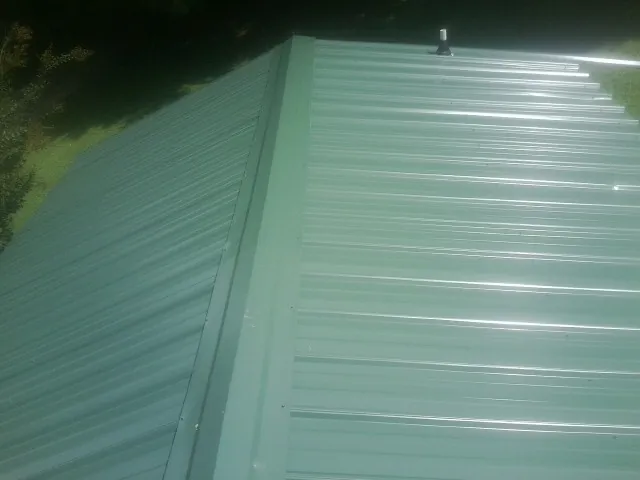 New green metal panels meeting at the ridge of a roof — Flat Roof Repair work by our crew in Brock
