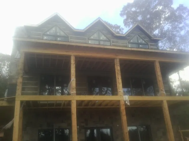 Dormers and porch framing on a large log home under construction — Roof Coating work by our crew in Brock