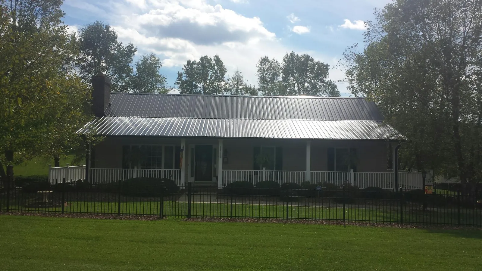Gray metal roof on a brick ranch with a full width front porch — Gutter Guard Installation work by our crew in Brock